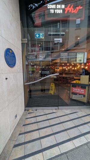 Glass door with metal handle on right. Pull from handle to open.