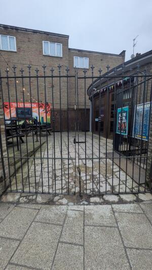 From back left of venue facing right. Metal gate ahead leading to outdoor seating area. Pull from centre to open.