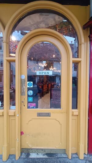 Yellow-framed glass door. Push handle on left to open.