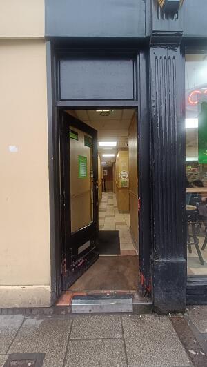Black wood-framed glass door to venue. Push handle on right to open.
