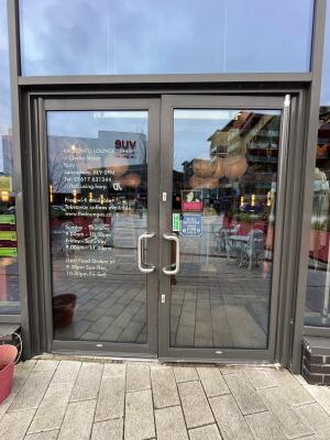 Dark metal-framed glass doors. Pull from metal handles at centre to open.