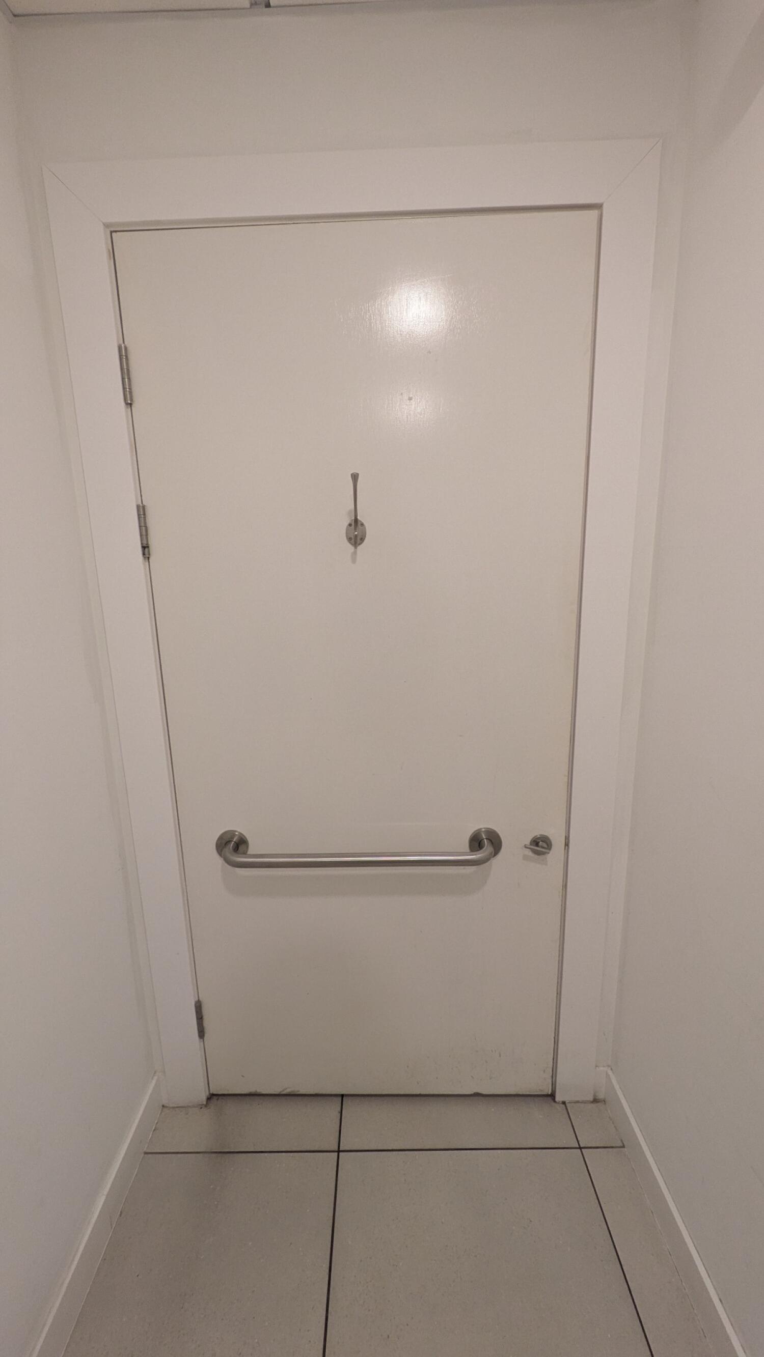 Back of rail. Grab rail in centre. Pull from metal handle on right to open.