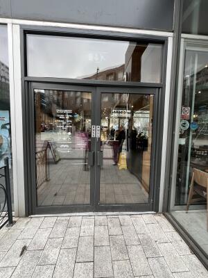 Dark metal-framed glass doors. Pull from handles at centre to open.
