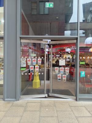 Double glass doors with metal frames. Push from metal handles at centre to open.