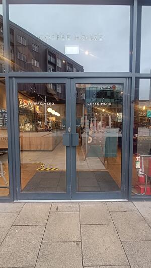 Dark metal-framed glass doors to venue. Push from handles at centre to open.
