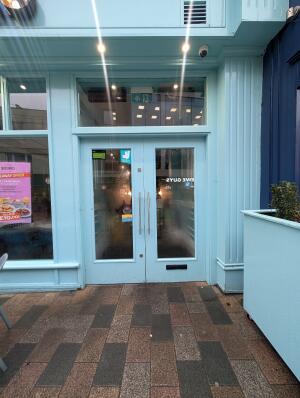 Light blue wood-framed glass doors. Push from metal handles at centre to open.