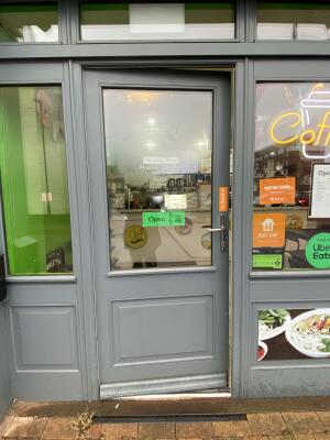 Grey metal-framed glass door. Push from silver metal handle on right to open.