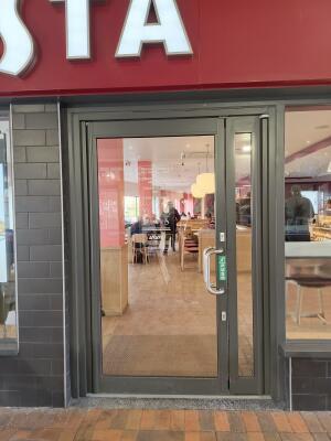 Dark grey metal-framed single glass door ahead. Push from handle on right to open.