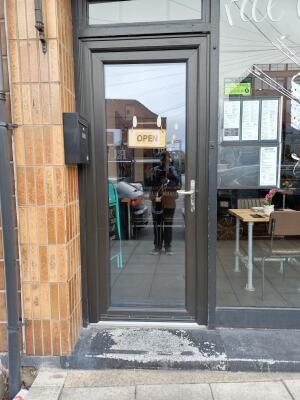 Black metal-framed glass door ahead. Push from handle on right to open.