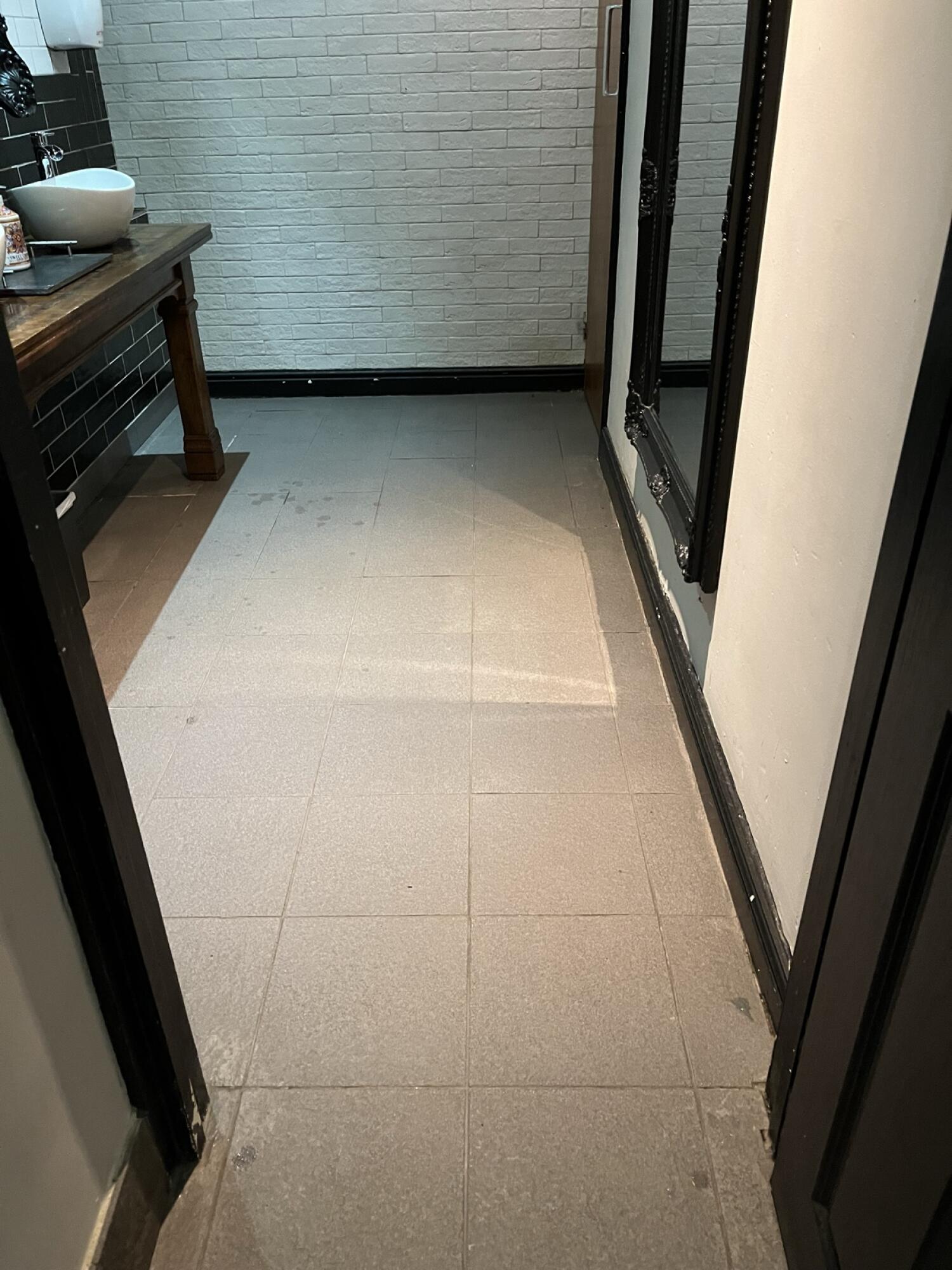 Sink on wooden counter to left. Door ahead at end of path.