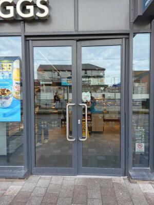 Grey metal-framed glass doors to venue. Push from metal handles at centre to open.