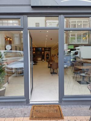 Grey metal-framed glass door. Push from handle on right to open.