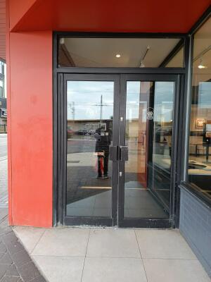 Black metal-framed glass doors ahead. Pull from handles at centre to open.