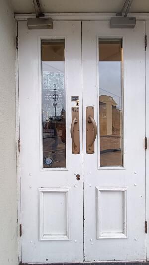 White wood-panelled glass doors to venue. Pull handles at centre to open.