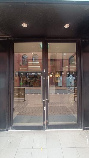 Black metal-framed glass doors to venue. Pull from metal handles at centre to open.