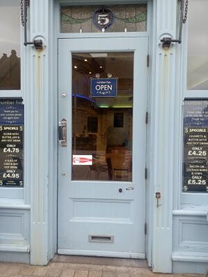 Light blue wooden-framed glass door. Pull from metal handle on left to open.