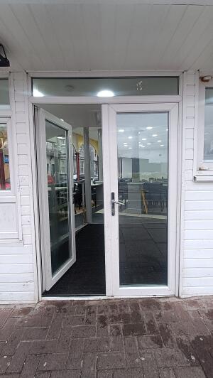 White metal-framed glass doors to venue. Push from handle in centre to open.