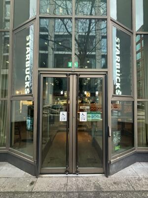 Brown metal-framed glass doors ahead. Doors open automatically from centre.