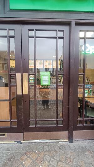 Dark wood-framed glass doors to venue. Push from metal plate on left to open.
