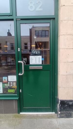 Green metal-framed glass door to venue. Push from metal handle on left to open.