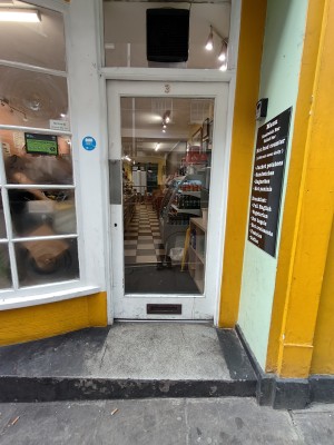 Facing white framed glass door. Push from left to open.