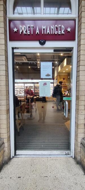 Glass door with white metal frame ahead. Push metal handle on right to open.