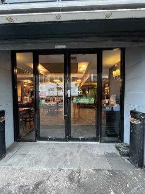 Black metal-framed glass doors. Pull from metal handles at centre to open.