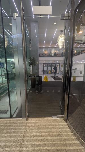 Glass door with metal frame. Pull from handle on left to open.