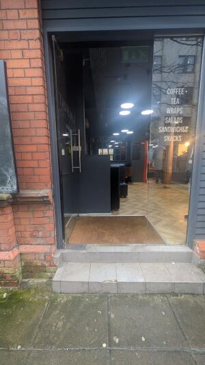 Glass door. Push on right to open. Two steps up before door. Doormat immediately after door.