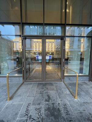 Brown metal-framed glass doors. Press button on pillar to open.