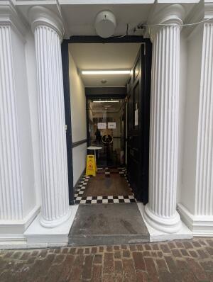 Black frame archway in front. Full glass doors at back. Silver handle in center. Pull to open.