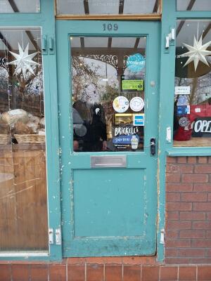 Teal wood-framed glass door ahead. Push from handle on right to open.