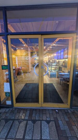 Yellow metal-framed glass doors. Push from centre to open.