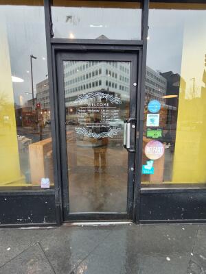 Black metal-framed glass door. Push from metal handle on right to open.