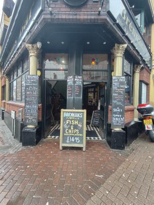 Black wood-framed glass doors on left and right. A frame sign in centre obstructing doors.