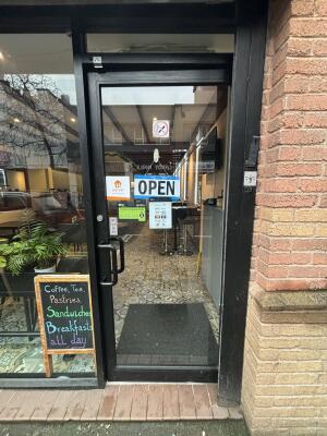 Black metal-framed glass door ahead. Push from handle on left to open.
