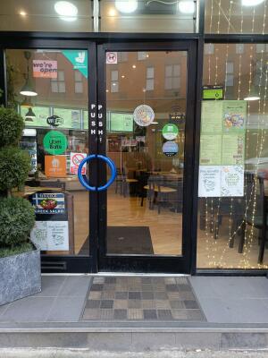 Black metal-framed glass doors. Push from blue handles at centre to open.