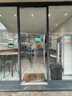 Black metal-framed glass door ahead. Push from handle on right to open.
