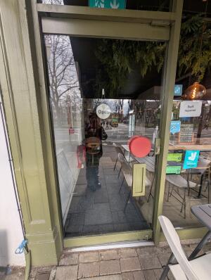 Green metal-framed glass door. Push from handle on right to open.