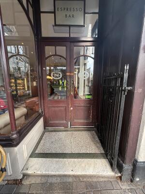 Black metal frame door leading to main entrance behind.