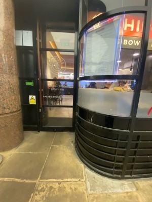 Glass door with black frame ahead. Pull from wooden handle on left to open.
