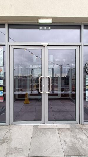 Grey metal-framed glass doors to venue. Push from metal handles at centre to open.