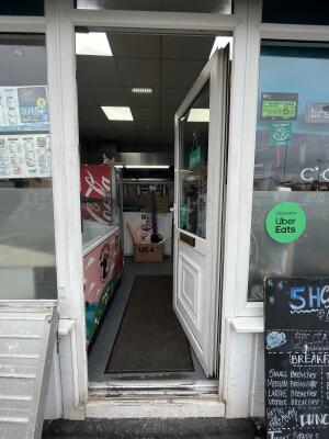 White-framed glass door. Push from handle on right to open. Small step at foot of door, doormat inside.