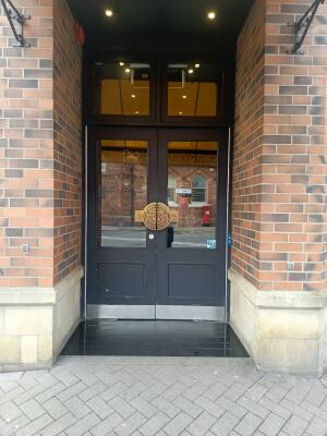 Black wood-framed glass doors. Push button on right of doors to open.