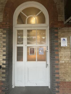 From platform facing venue. White wood-framed glass door ahead. Push from metal handle on right to open.