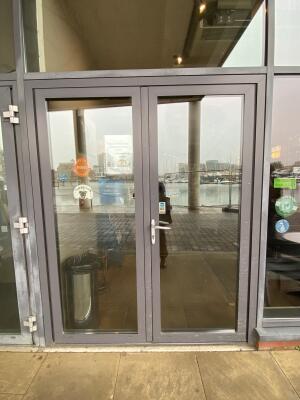 Grey metal-framed glass doors. Push from left handle on right door to open.