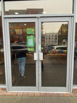 Grey metal-framed glass doors. Push from metal handles at centre to open.