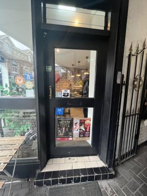 Black metal-framed glass door. Push from handle on left to open.