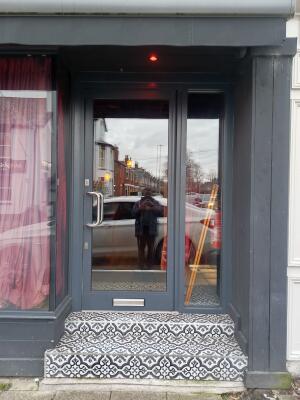 Dark grey metal-framed glass door ahead. Push from handle on left to open.