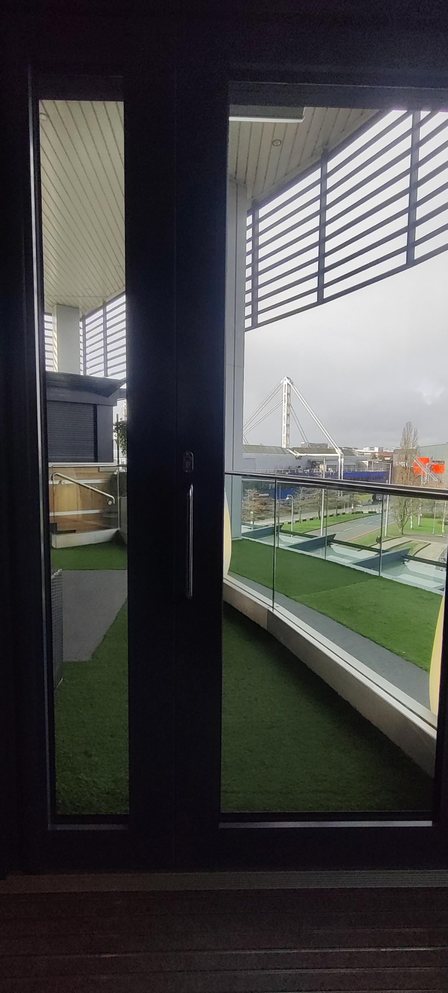 From end of path facing left. Blue-framed glass door. Pull from handle on left to open.